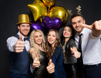 celebration, people and holidays concept - happy friends at christmas or new year party with balloons over black background showing thumbs up